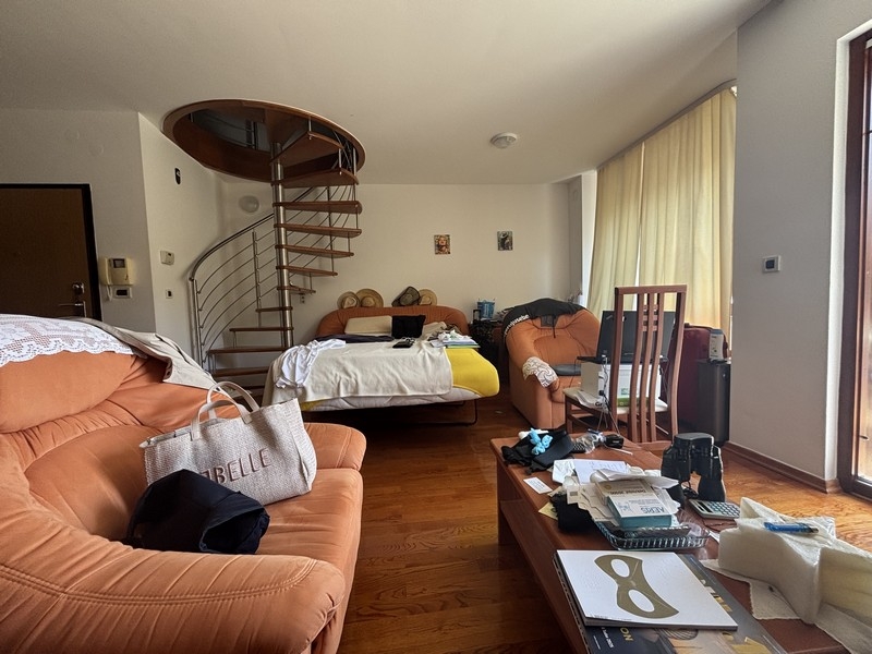 Séjour avec canapés et escalier en colimaçon menant à l'étage