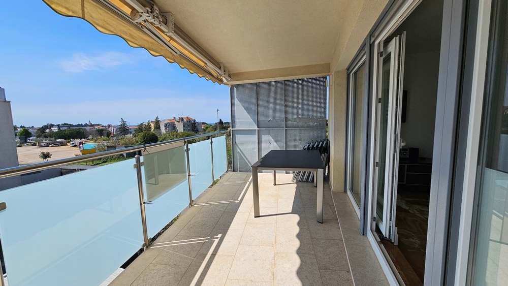 Balcon couvert avec coin salon et vue en direction de la mer