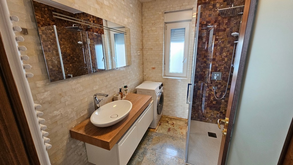 Salle de bains avec douche, lave-linge et lumière du jour