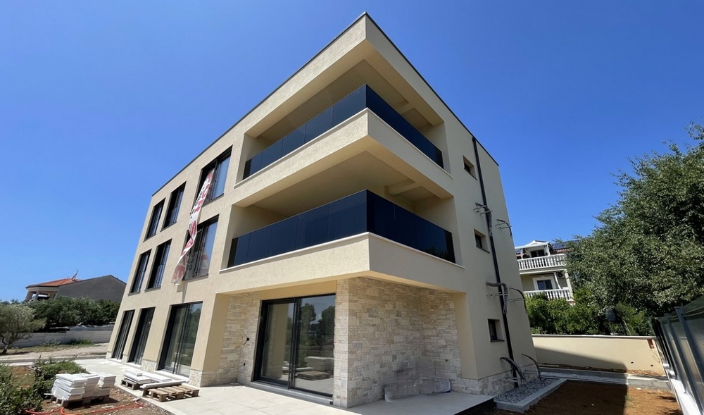 Immeuble neuf A3945 vu de côté avec balcons et façade en pierre naturelle