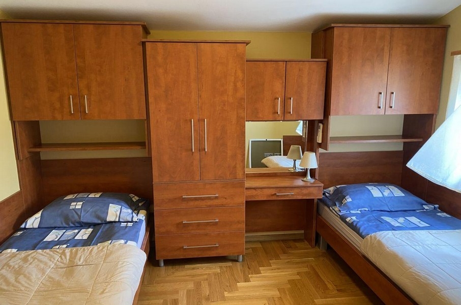 Chambre avec lits simples et meubles en bois dans un appartement de vacances