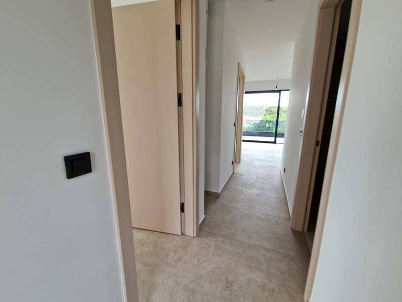 Long couloir avec portes et vue sur la terrasse