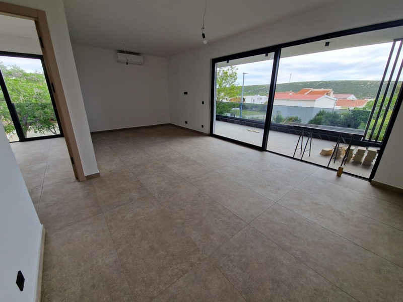 Salon avec climatiseur et portes donnant sur la terrasse