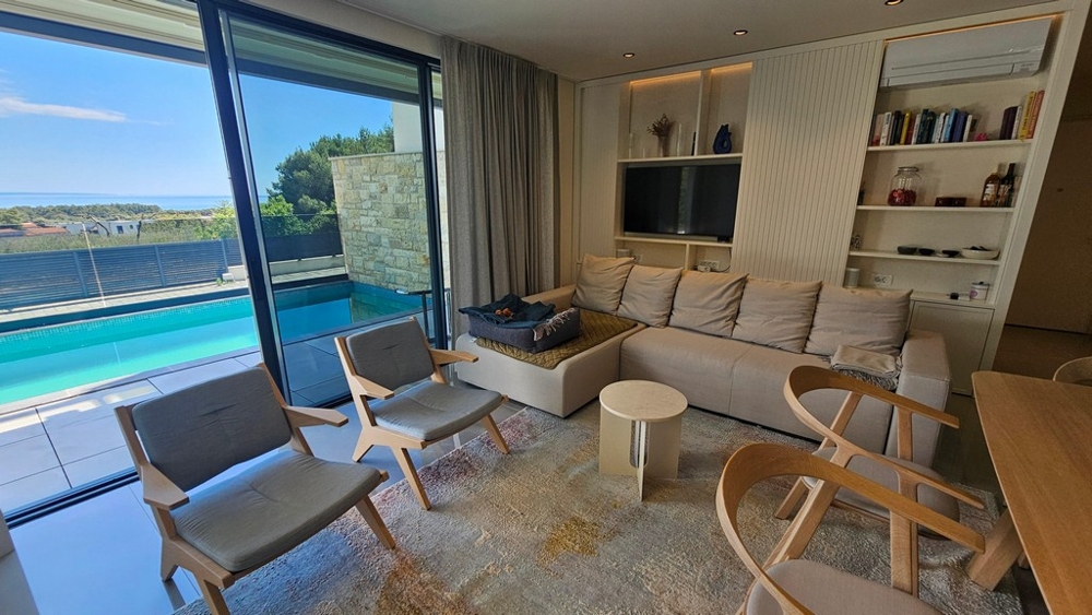 Salon moderne avec vue sur la piscine et la mer