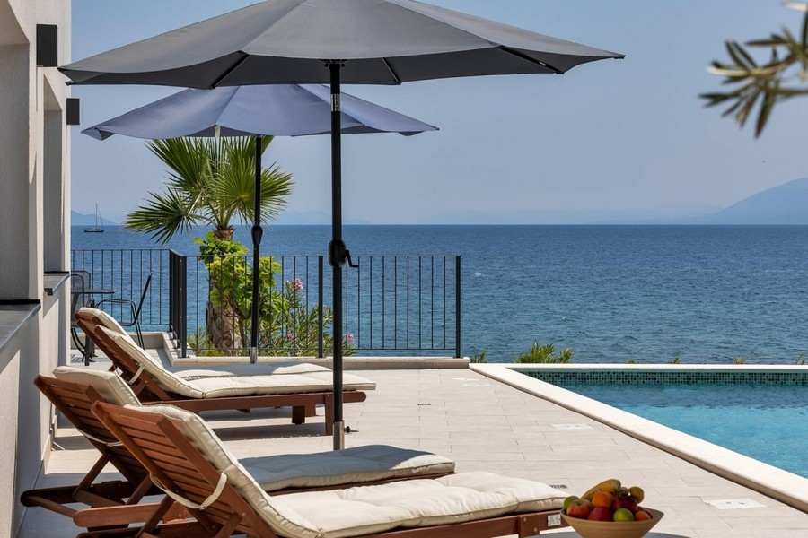 Terrasse avec bains de soleil et vue mer au bord de la piscine