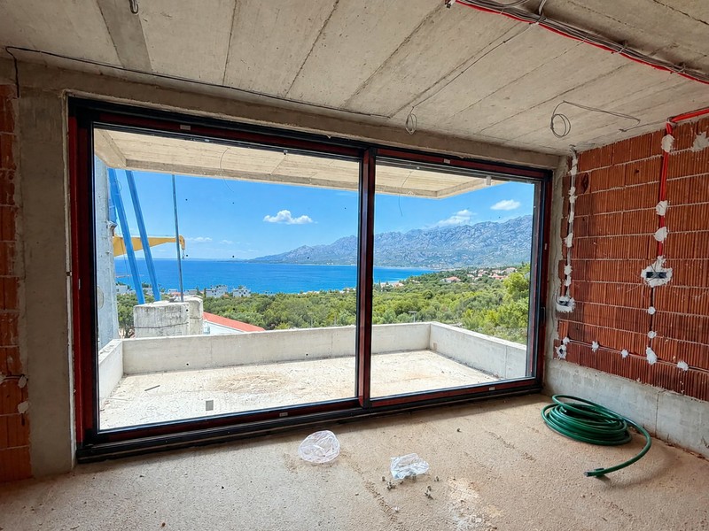 Pièce en gros œuvre avec porte coulissante à hauteur d'étage et vue sur la mer