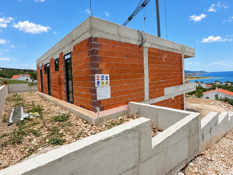 Gros œuvre avec fenêtres posées, panneaux de chantier et murs en béton