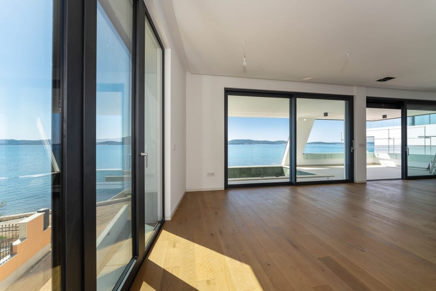 Séjour avec plancher en bois et fenêtres à hauteur d'étage avec vue mer
