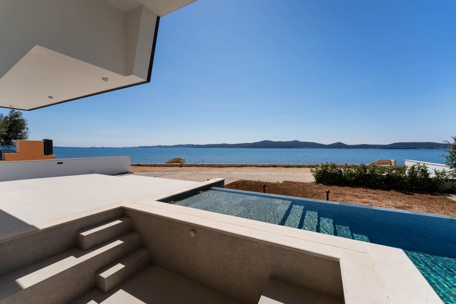 Terrasse couverte avec marches vers la piscine et vue mer