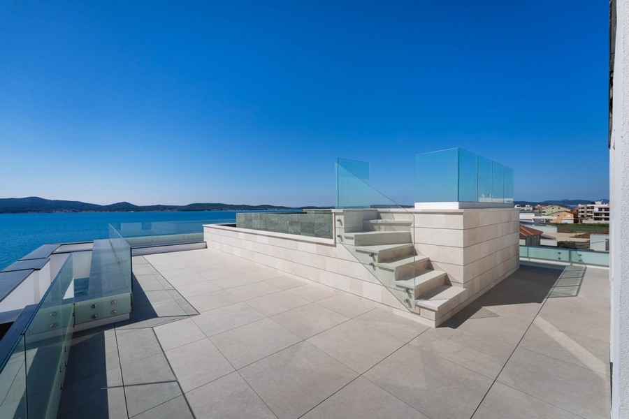 Toit-terrasse avec escalier et garde-corps en verre au bord de la mer