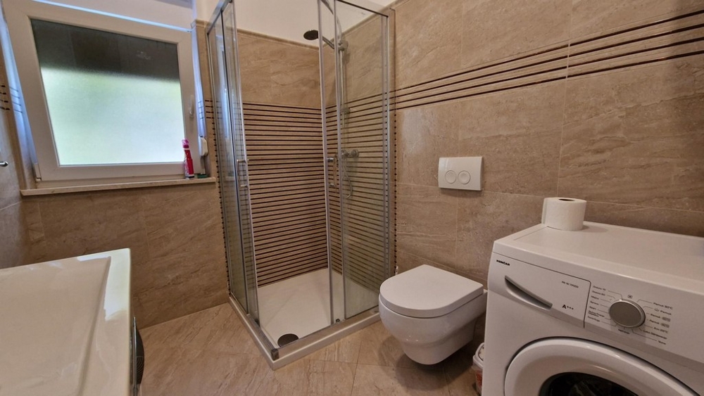 Salle de bains avec cabine de douche et lave-linge à Njivice