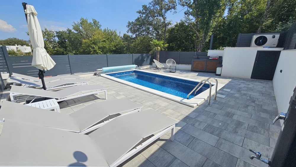 Jardin avec piscine chauffée et bains de soleil de l'appartement à Malinska