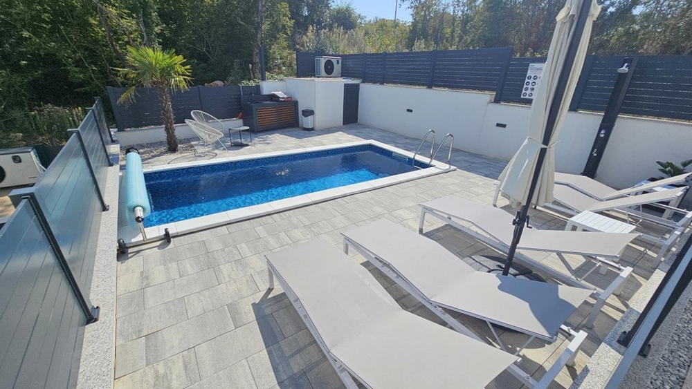 Piscine et solarium dans le jardin privé de l'appartement à Malinska