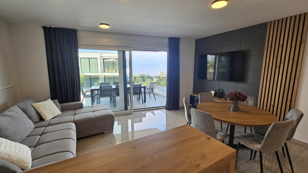 Séjour avec vue mer à travers la baie vitrée de l'appartement à Malinska