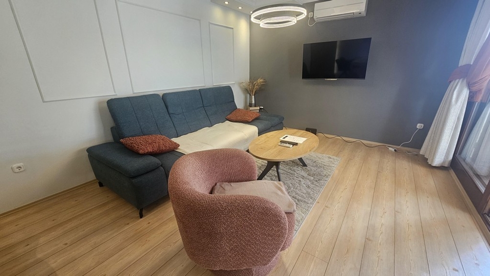 Salon avec canapé et télévision dans l'appartement rénové