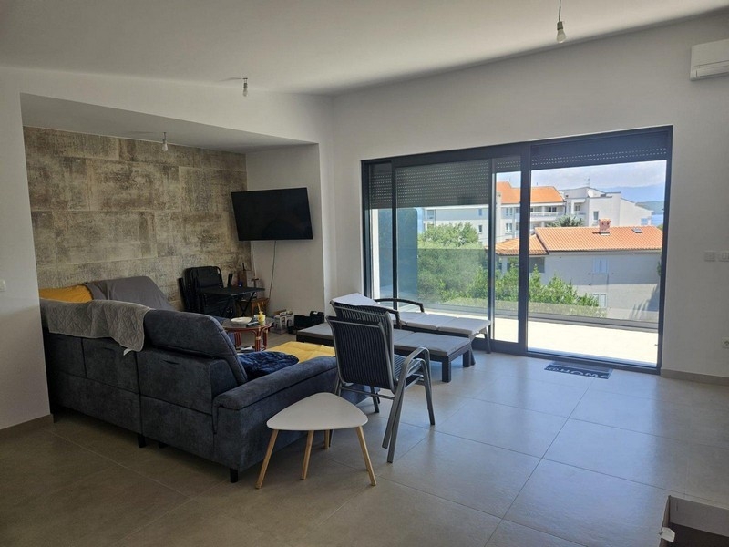 Séjour avec canapé, mur en pierre naturelle et accès au balcon