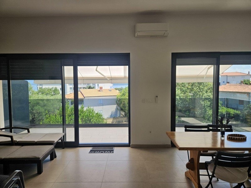 Espace repas avec table en bois et vue sur le balcon et la mer