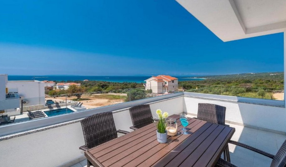 Table de balcon avec chaises en osier et vue sur la piscine et la côte