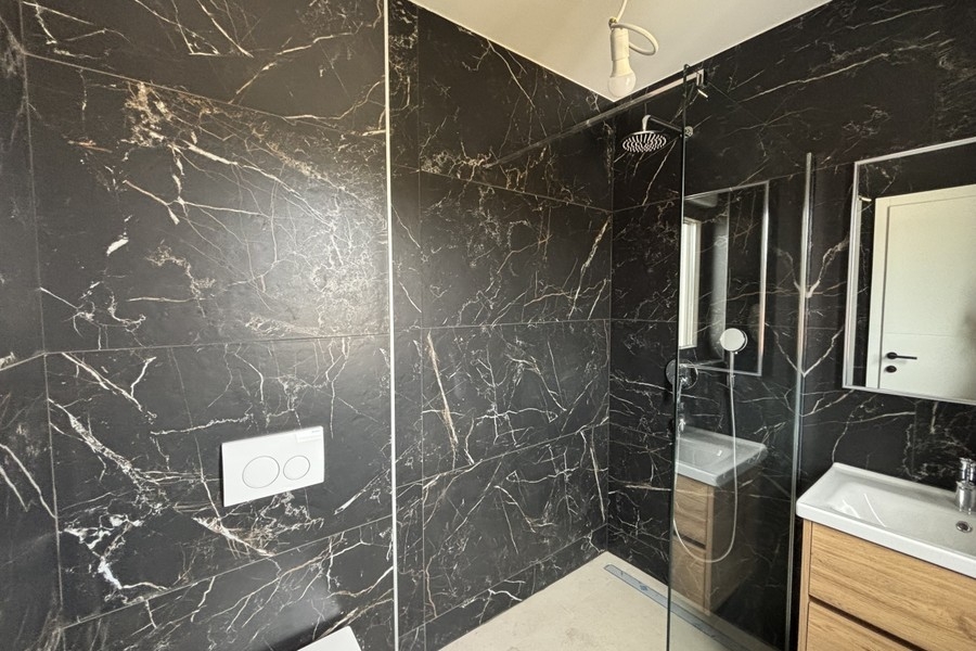 Salle de bains avec carreaux de marbre foncé et douche