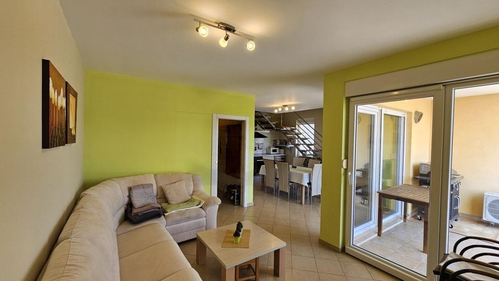 Pièce de vie avec canapé et accès au balcon