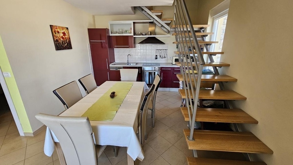 Espace repas avec cuisine et escalier vers les combles