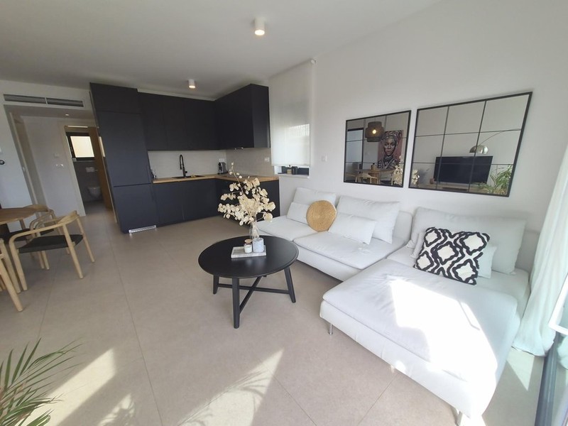 Salon avec canapé blanc et kitchenette