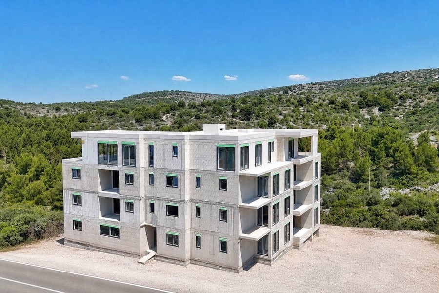 Immeuble neuf de quatre niveaux devant des collines boisées
