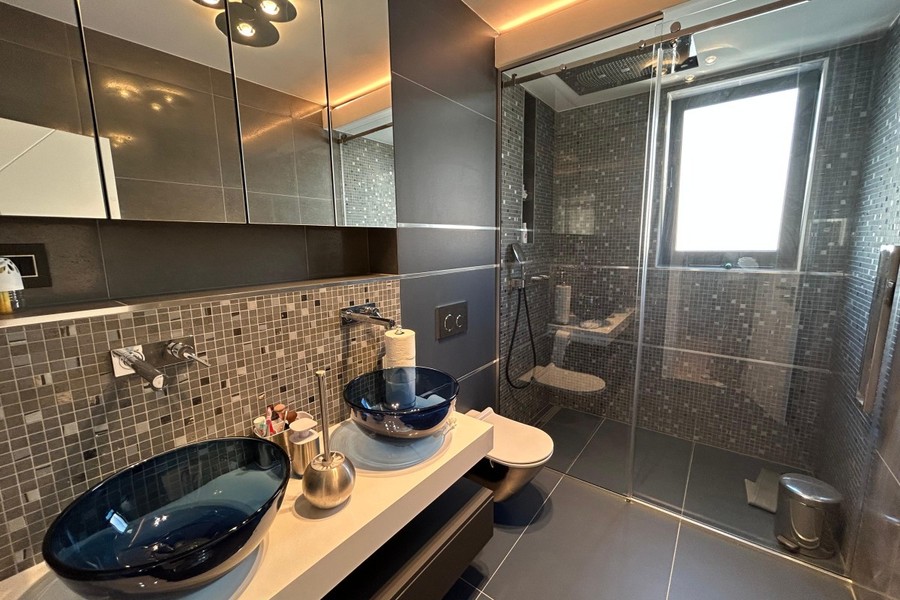 Salle de bains avec deux vasques en verre et douche