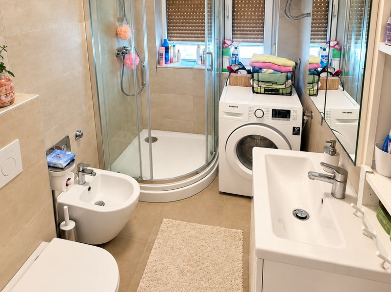 Salle de bain avec douche et machine à laver