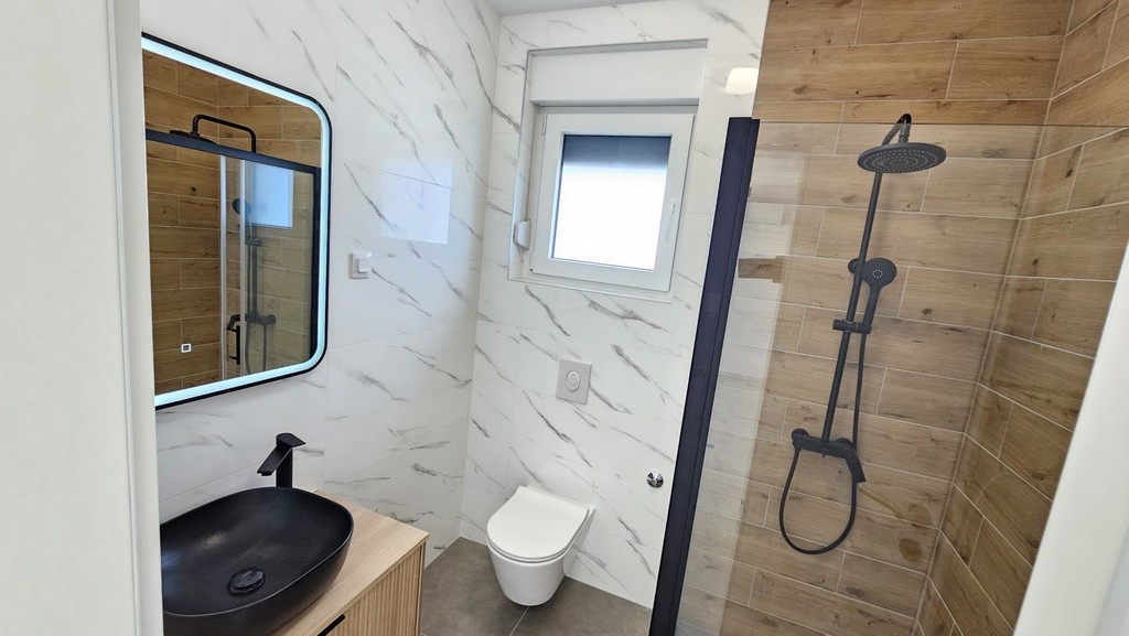 Salle de bains avec douche de pluie et miroir