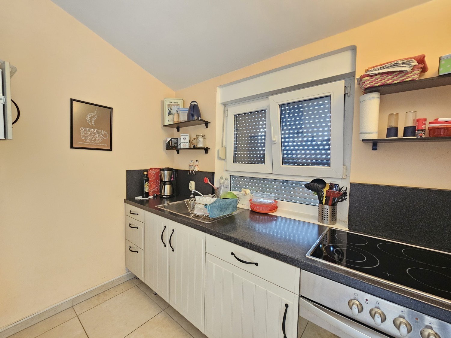 Cuisine avec façades blanches, plaque de cuisson et fenêtre