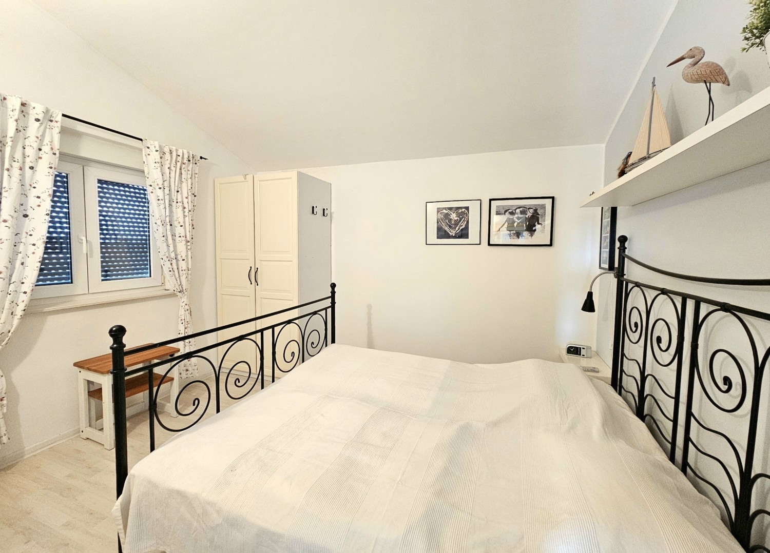 Chambre avec lit double en métal sous le toit en pente