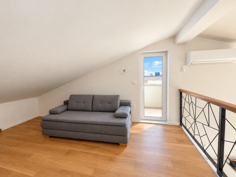 Mezzanine avec canapé-lit et porte-fenêtre du balcon