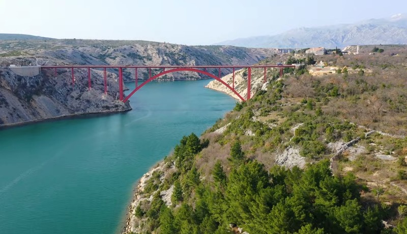 Pont d'acier rouge au-dessus du détroit devant les montagnes