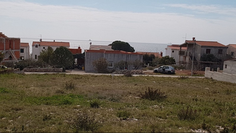 Terrain en friche entre des maisons avec la mer à l'arrière-plan