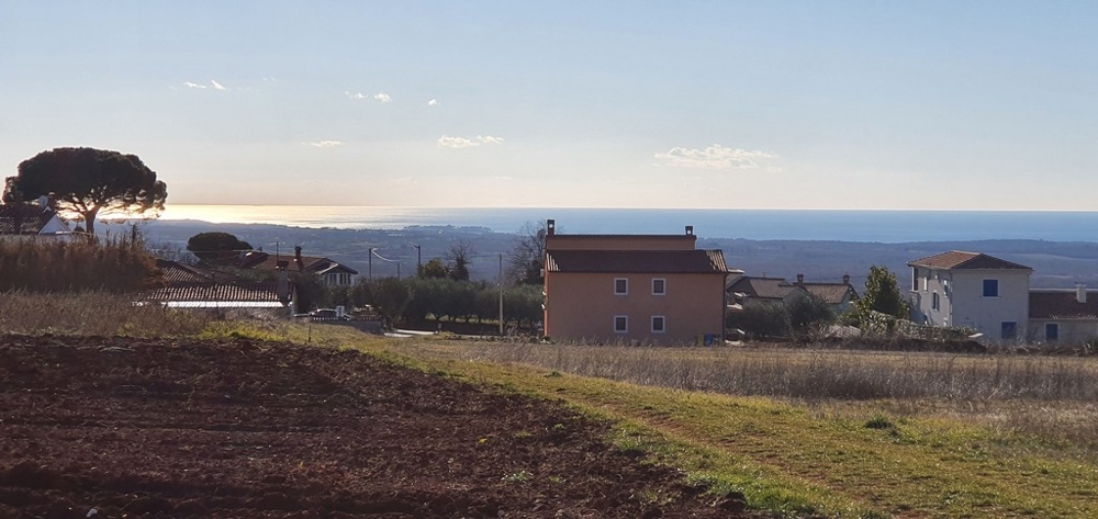 Champ labouré avec maisons et mer à l'horizon