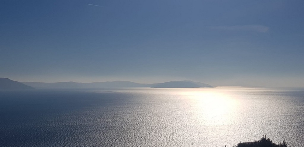 Reflet du soleil sur la mer avec silhouettes d'îles dans la brume