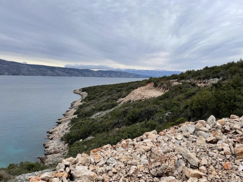 Rivage pierreux avec maquis sous un ciel couvert