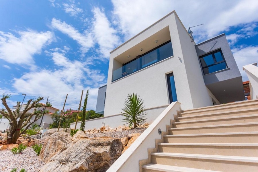 Villa blanche au-dessus de l'escalier extérieur avec yucca dans le massif de gravier