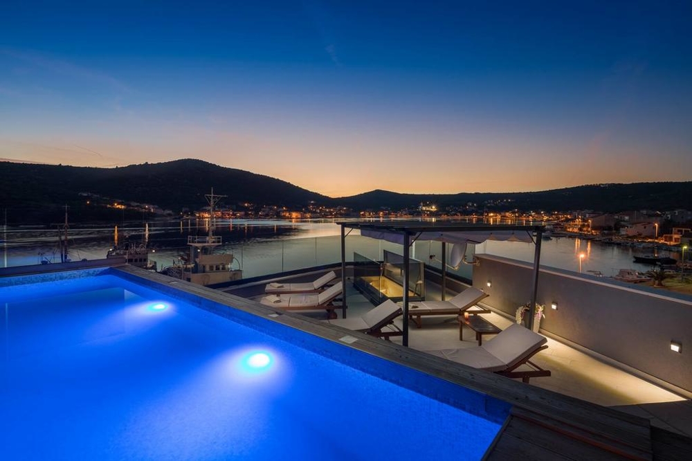 Piscine éclairée avec bains de soleil au-dessus du port le soir