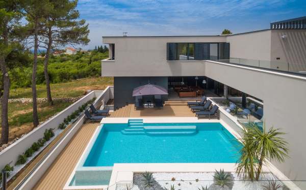 Piscine avec terrasse en bois et parasol devant la villa