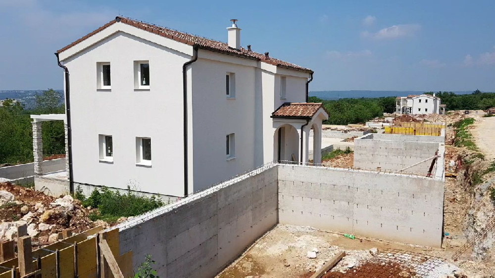 Maison blanche à toit de tuiles derrière le mur de soutènement en béton