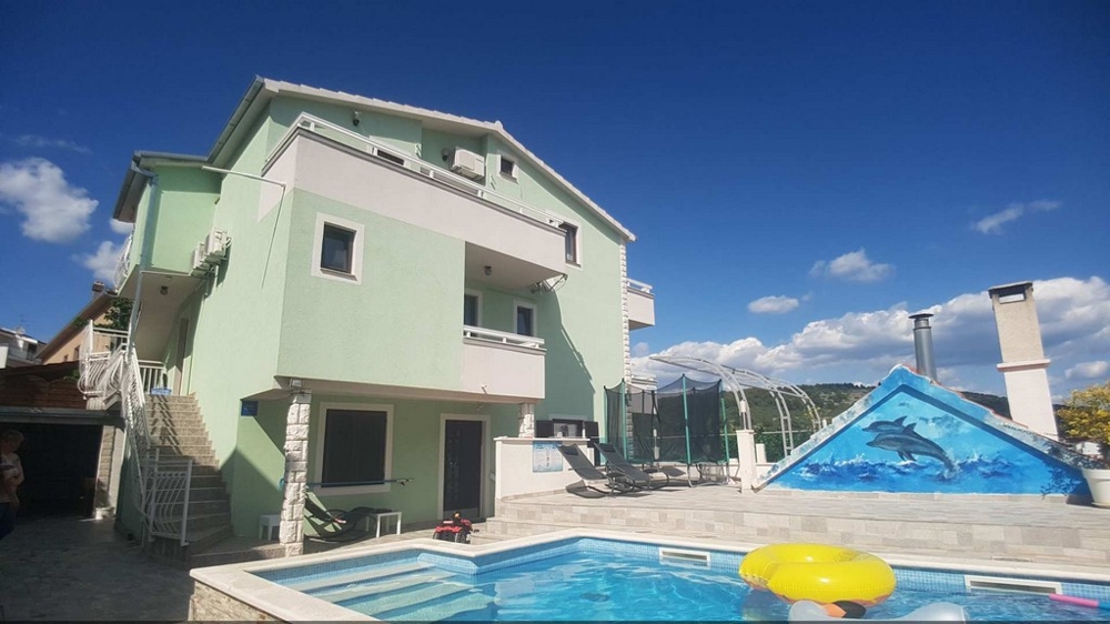 Maison verte avec piscine et couverture de piscine dans la cour