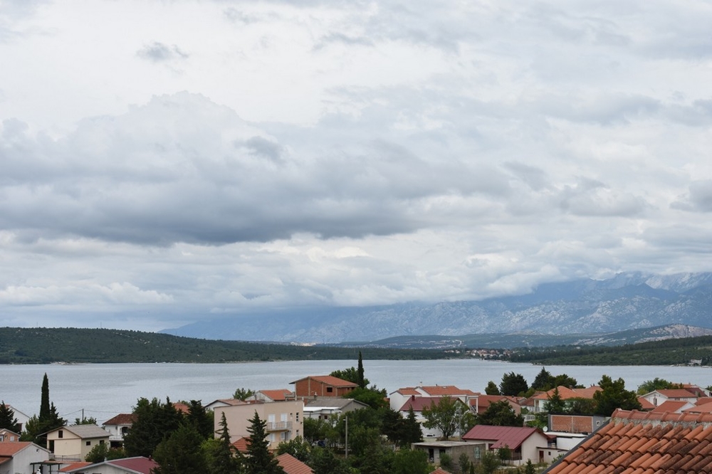 Toits en tuiles devant la baie avec montagnes sous les nuages