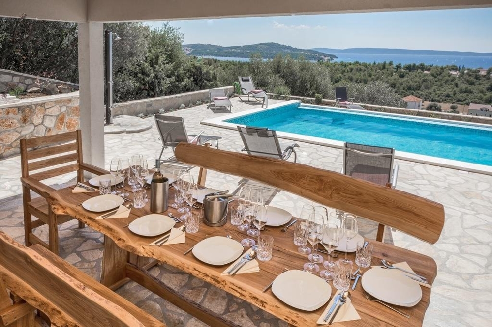 Vue depuis le coin repas de la terrasse sur la piscine et la mer.