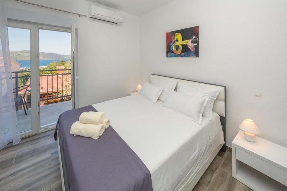 Une chambre avec un lit double et un balcon en Croatie.