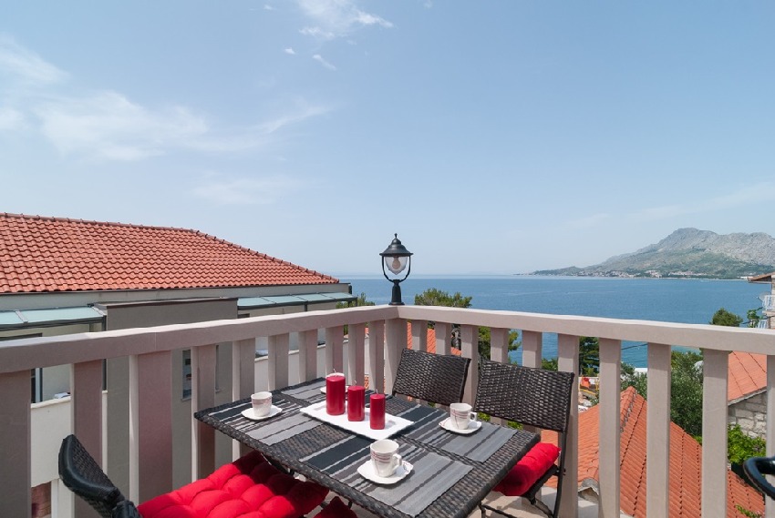 Table de balcon dressée avec coussins rouges au-dessus du toit de tuiles