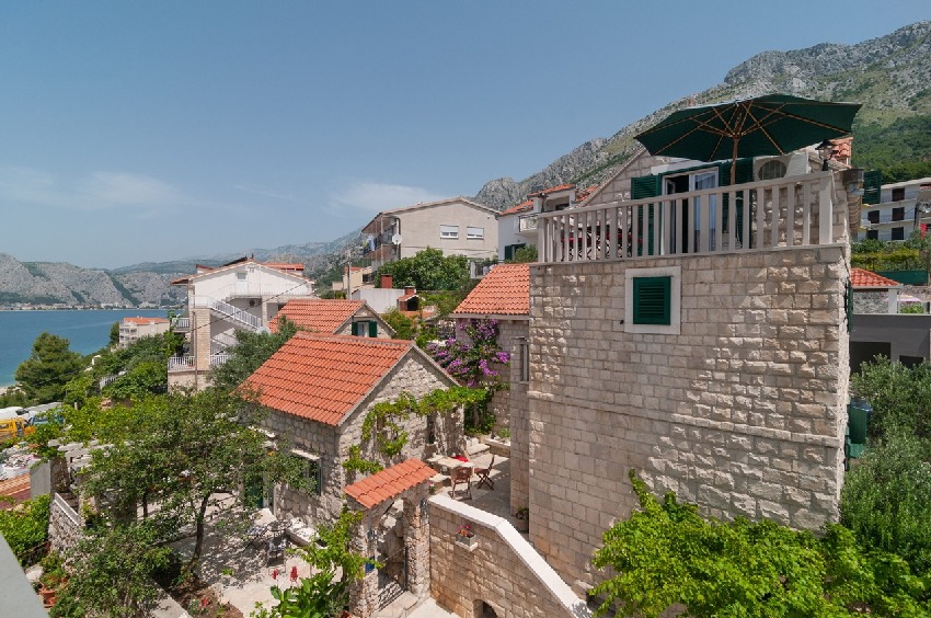 Maisons en pierre avec toit-terrasse et parasol à flanc de montagne