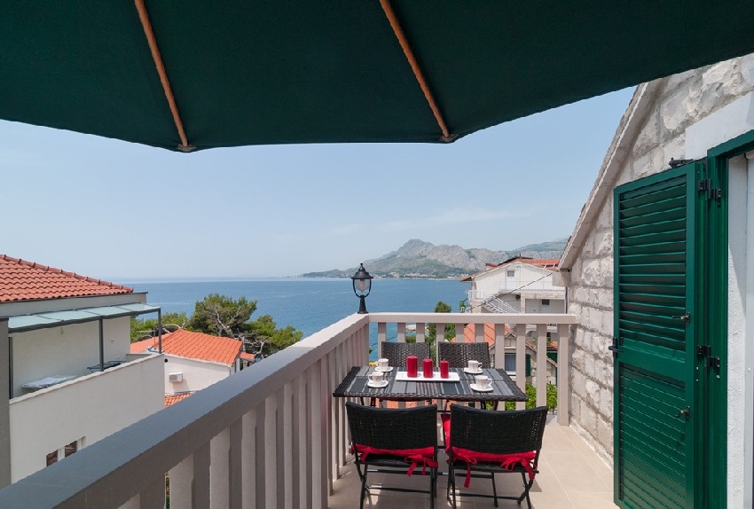 Balcon sous un parasol vert avec vue sur la baie et les montagnes