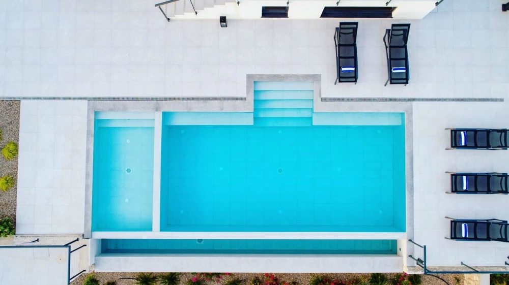 Piscine vue d'en haut avec bains de soleil sur la terrasse de la piscine